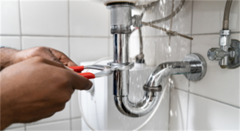 Person fixing water leak under bathroom sink