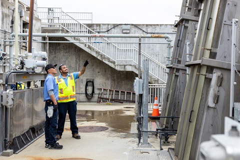 Two workers inspect a bar screen